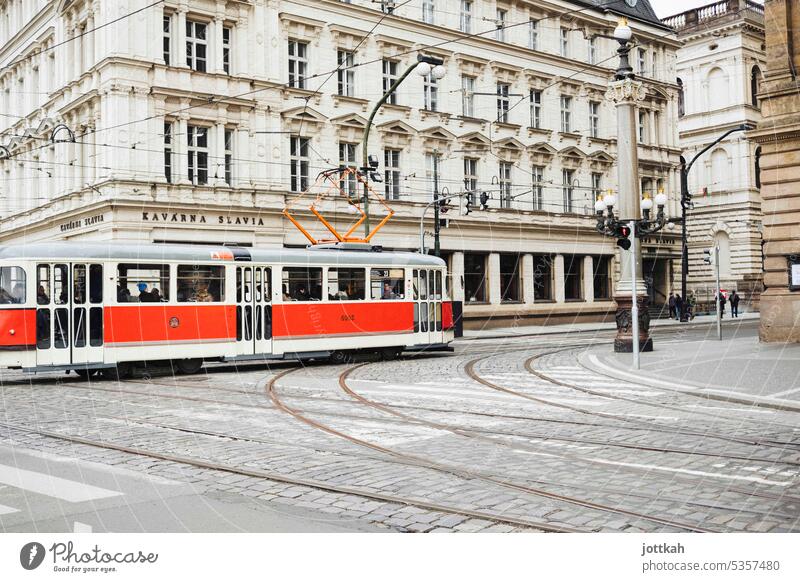 A red streetcar travels through Prague Town Czech Republic Capital city Europe urban Mobility public transportation Public transit Tram rails Red Contrast
