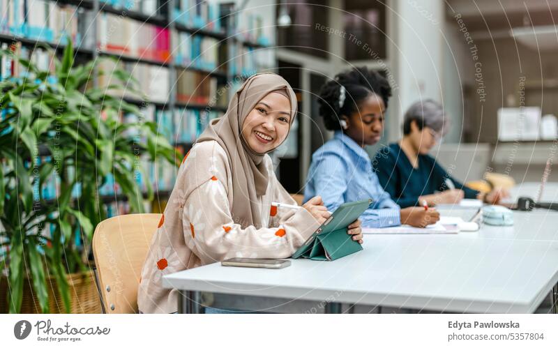 Multiethnic group of students sitting in a library and studying together real people teenager campus positive exam knowledge confident academic adult lifestyle