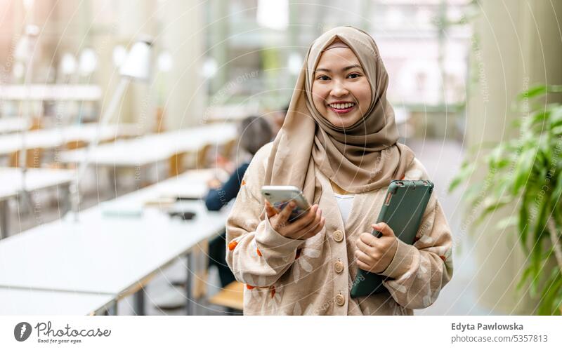 Portrait of asian muslim female student standing in a library real people teenager campus positive exam knowledge confident academic adult lifestyle academy