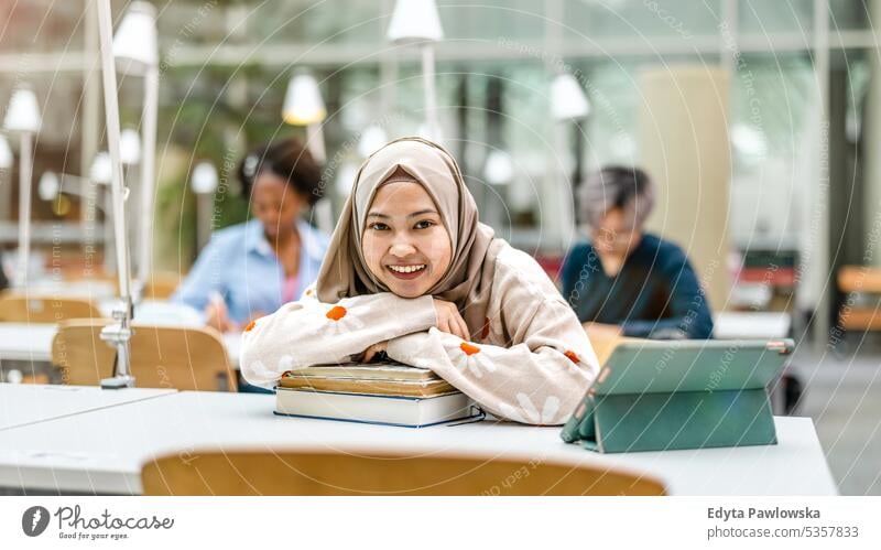 Multiethnic group of students sitting in a library and studying together real people teenager campus positive exam knowledge confident academic adult lifestyle