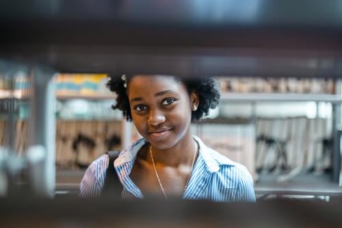 Portrait of black female student standing in a library real people teenager campus positive exam knowledge confident academic adult lifestyle academy adolescent