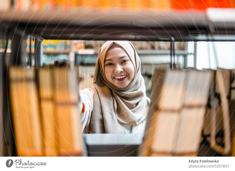 Portrait of asian muslim female student standing in a library real people teenager campus positive exam knowledge confident academic adult lifestyle academy