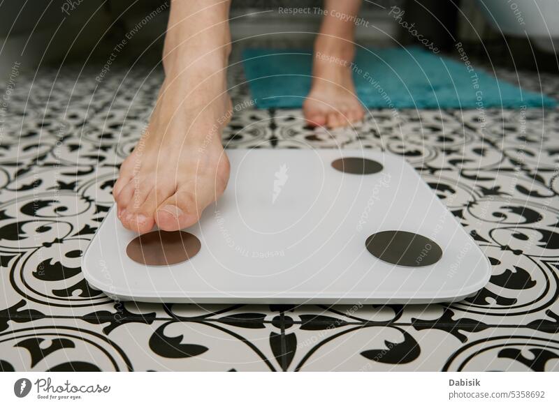 Woman checking her weight on weighing scales in bathroom control woman feet digital body measure diet health background healthy balance fat standing fitness