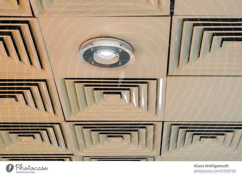 Ceiling lining with openings of an air conditioner in a shopping center. In addition, a decorative lamp. Ceiling cladding Air conditioning square Square