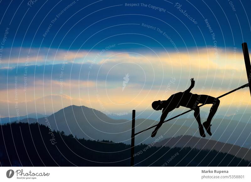 Silhouette of athlete competing in pole vault at dusk victory success athletics sportsman silhouette jumping landscape mountains altitude background clouds hill
