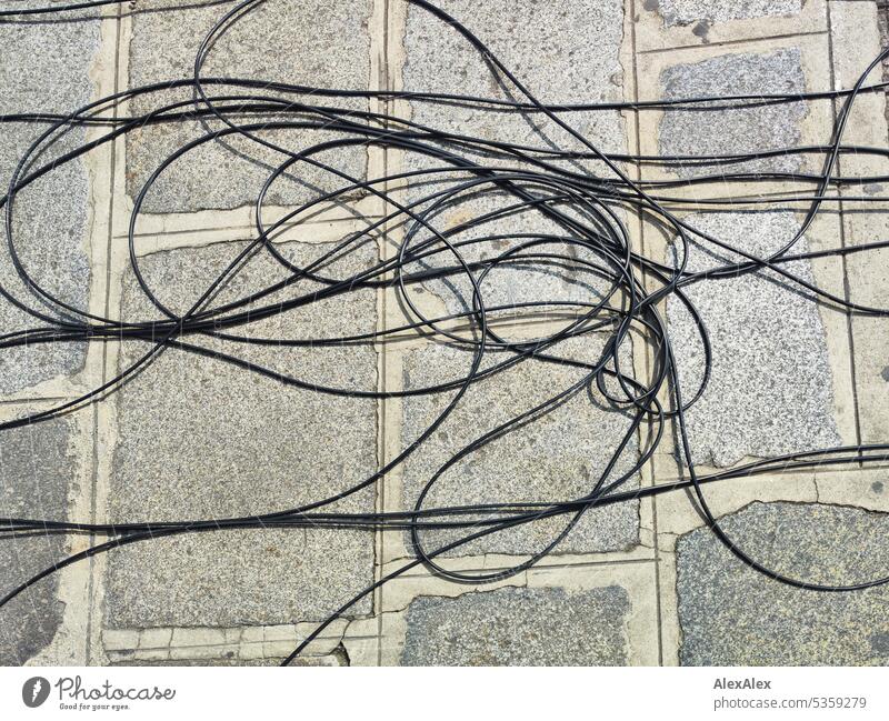 Black long cable on the sidewalk, moderately tangled Ground off power line Save energy Energy crisis Power transmission Transmission lines Energy industry