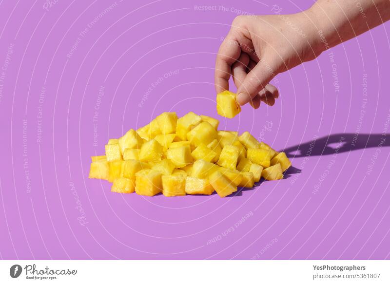Pineapple pieces on a purple background. Woman hand taking pineapple ananas bright close-up color concept copy space cubes cuisine cut out delicious dessert
