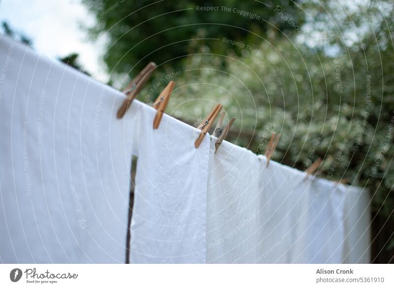 white washing on the line to dry washing line washing outside hung out to dry hung up to dry clothes on the line clothes line white sheets pegs domestic jobs