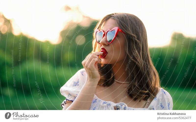 Sexy woman eating red ripe strawberry in sunset light. Stylish lady,closeup fresh fruit beautiful diet female food hand healthy nutrition organic summer tasty