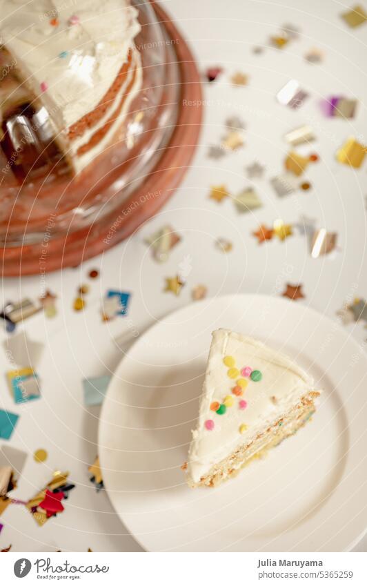 Confetti cake slice with colorful sprinkles and layered vanilla cake in covered cake stand surrounded by metallic confetti shapes confetti cake funfetti cake