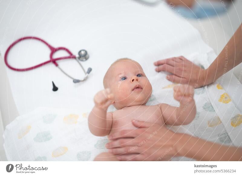 Baby lying on his back as his doctor examines him during a standard medical checkup baby infant boy pediatrician stethoscope heartbeat childhood medicine clinic