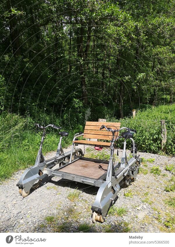 Bicycle trolley on gray gravel at a rest area in the green in the summer sunshine on the railroad line near Rinteln in the Weserbergland in the district of Schaumburg in Lower Saxony