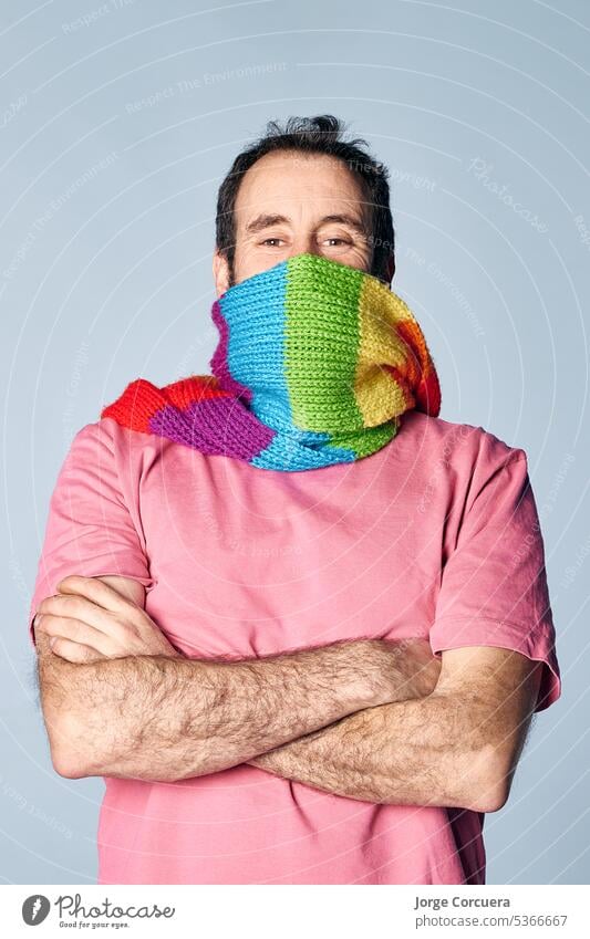 vertical portrait of madure man covering his face with a rainbow scarf. lgbt concept nature hispanic quir modern diversity white friendly young bisexual yellow