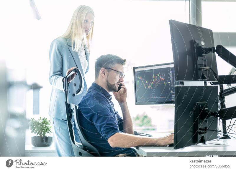 Stock broker business team trading online watching charts and data analyses on multiple computer screens in modern corporate work station office. trader market