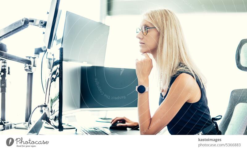 Female financial assets manager, trading online, watching charts and data analyses on multiple computer screens. Modern corporate business woman concept.
