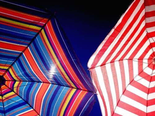 Two colorful umbrellas on the beach parasols Sunshade Summer Beach Summer vacation Sunlight Blue sky Ocean Cloudless sky Sunbathing sun protection