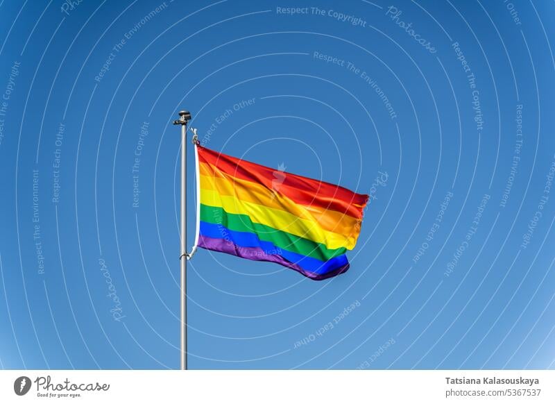 The rainbow flag of the LGBTQ community flies against blue clear sky Rainbow flag Waving Clear Blue sky Pride Equality Diversity Inclusion Celebration Identity