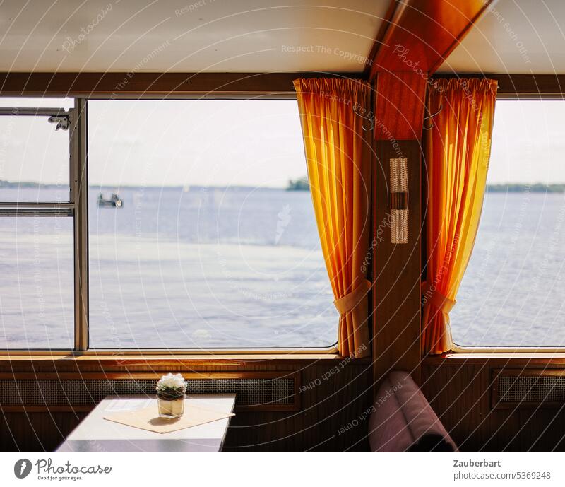 View of the lake from the window of a passenger ship with orange curtains Ferry Curtain bench Window Lake outlook Orange free time Table Flower arrangement