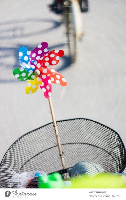 Colorful pinwheel attached to bicycle basket to entertain toddler child riding on front child seat on bike in summer. wind spinner cycling ride boy windmill man