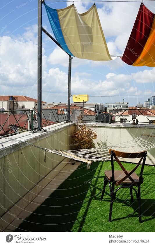 Old wooden chair, hammock and green artificial grass on the roof terrace of a hotel in Taksim district in summer sunshine on Istiklal Caddesi in Istanbul on the Bosphorus in Turkey