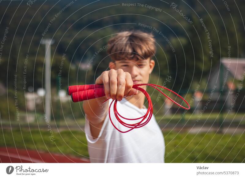 Brown-haired boy with an athletic build promotes the jump rope as one of the best tools for improving endurance, jumping power sport person sportsman practice