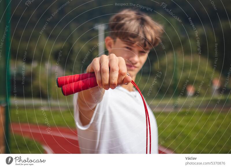 Brown-haired boy with an athletic build promotes the jump rope as one of the best tools for improving endurance, jumping power sport person sportsman practice