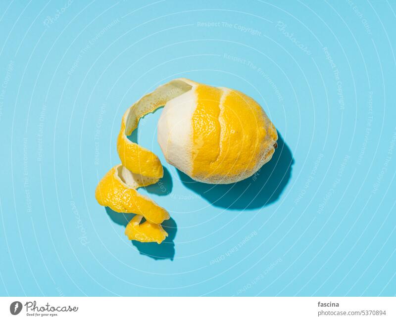 Lemon and spiral peel on blue background hardlight Lemon peel Blue background Minimalistic hard light concept Summer shell Menu Idea overhead from top to bottom
