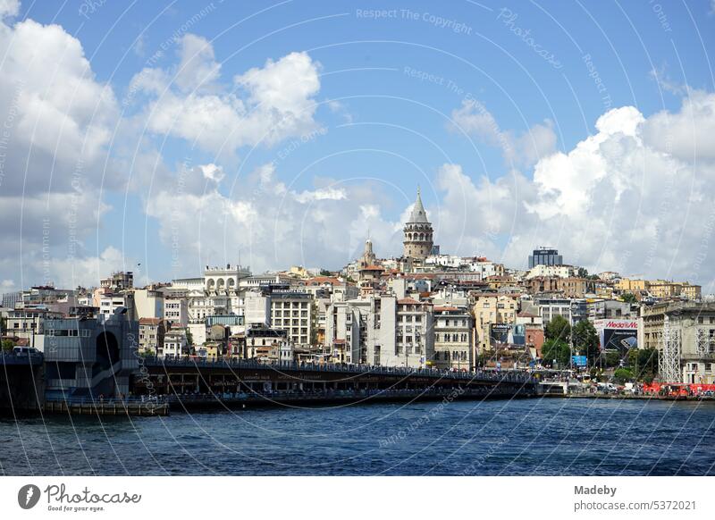 View from Galata Bridge in summer sunshine with blue sky and white clouds towards Galata Tower in Beyoglu district of Istanbul on Bosphorus and Golden Horn in Turkey