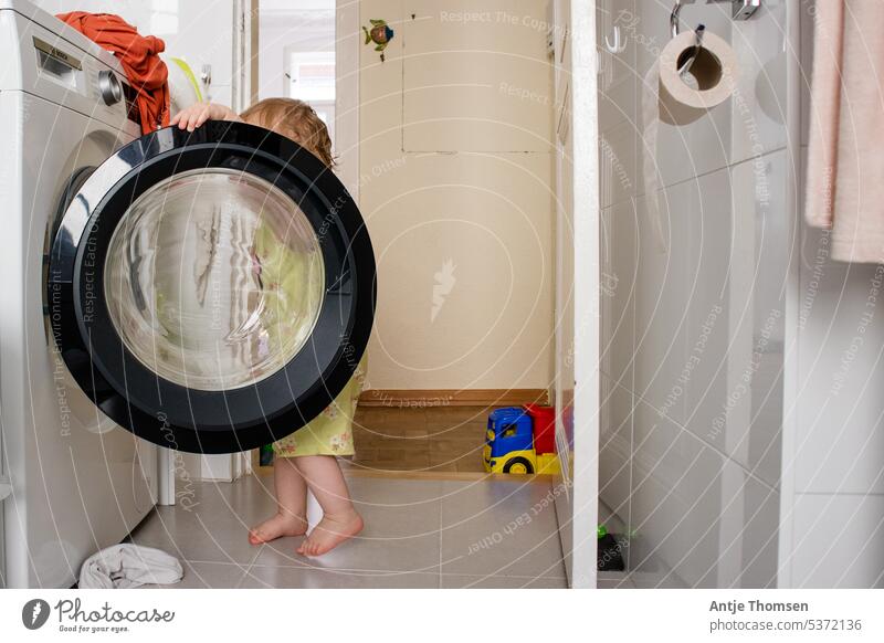 Toddler looks into open washing machine Washer montessori Child Washing Washing day Household Photos of everyday life Documentary