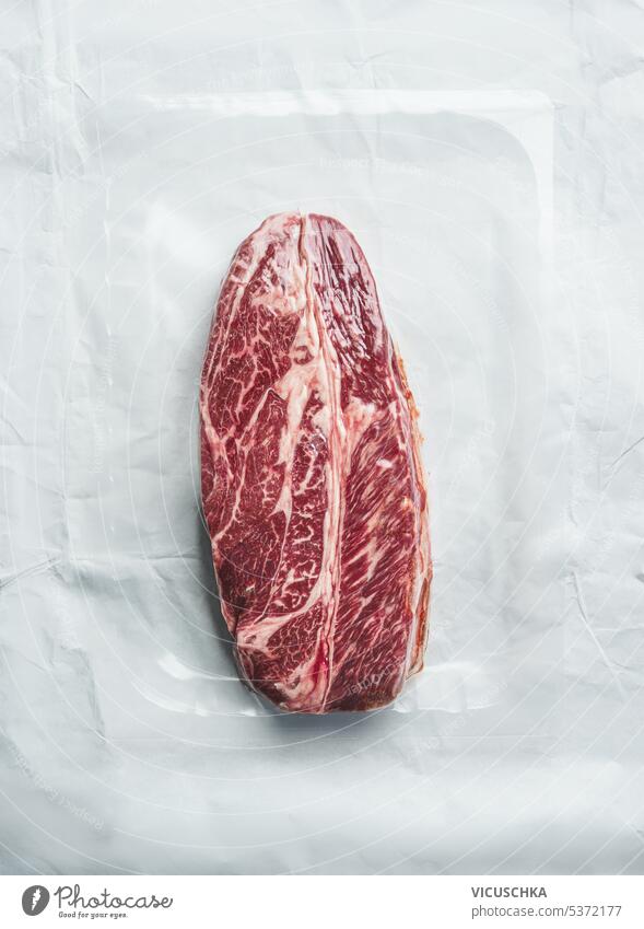 Excellent marbled raw beef steak in vacuum plastic packaging, top view excellent above background beefsteak copy space package uncooked food meat