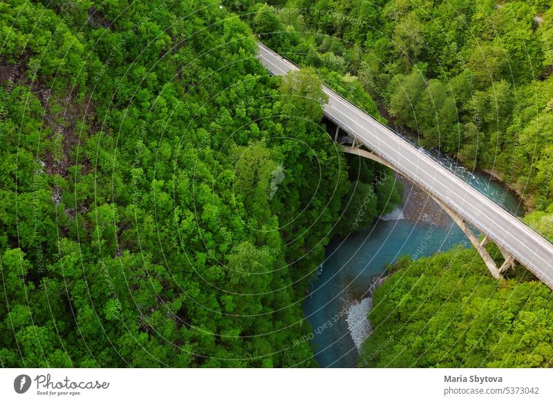 Amazing aerial top drone view of high-speed road and bridge over the river between the picturesque mountains. Top down view of picturesque mountain valley.