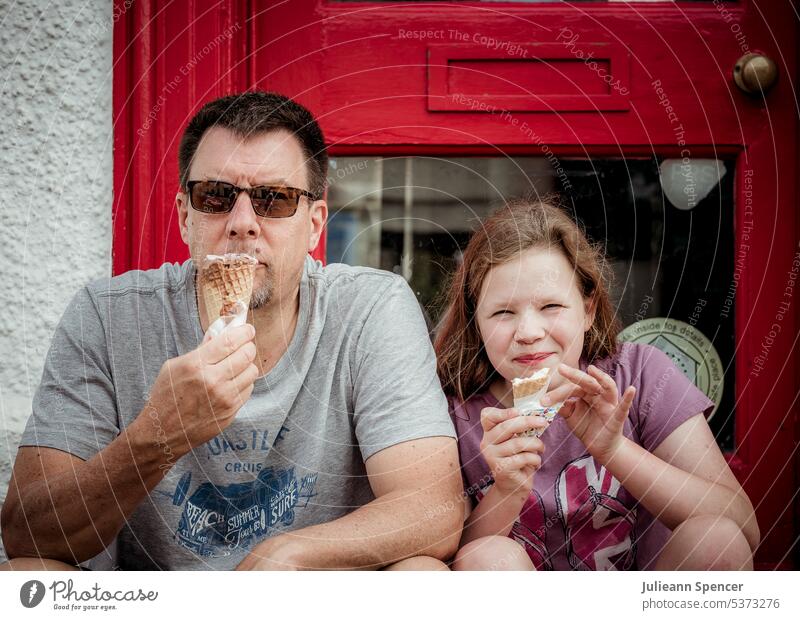 Father and daughter eating ice cream father man girl icecream sitting summer ice-cream sitting in doorway