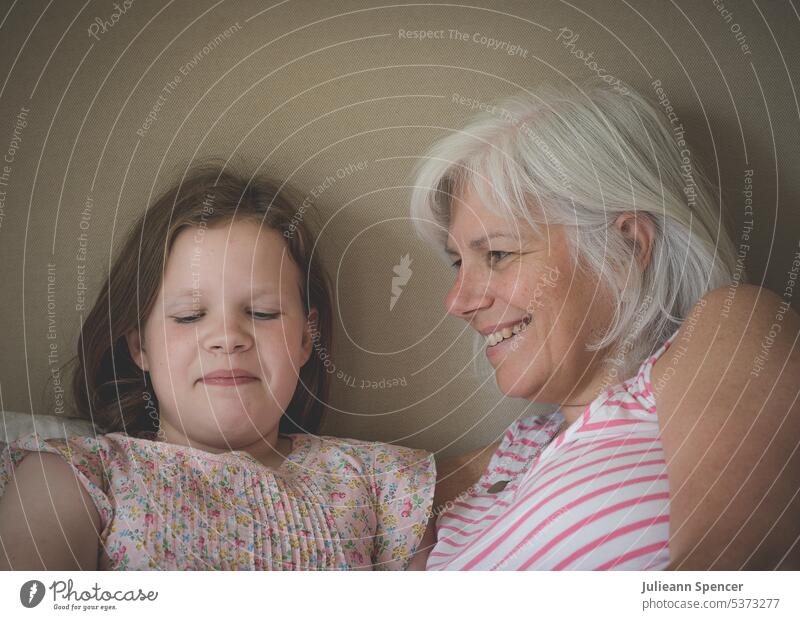 Mother and daughter laughing together young girl mother adult female grey older older parent child family love mom happiness smiling cheerful childhood woman