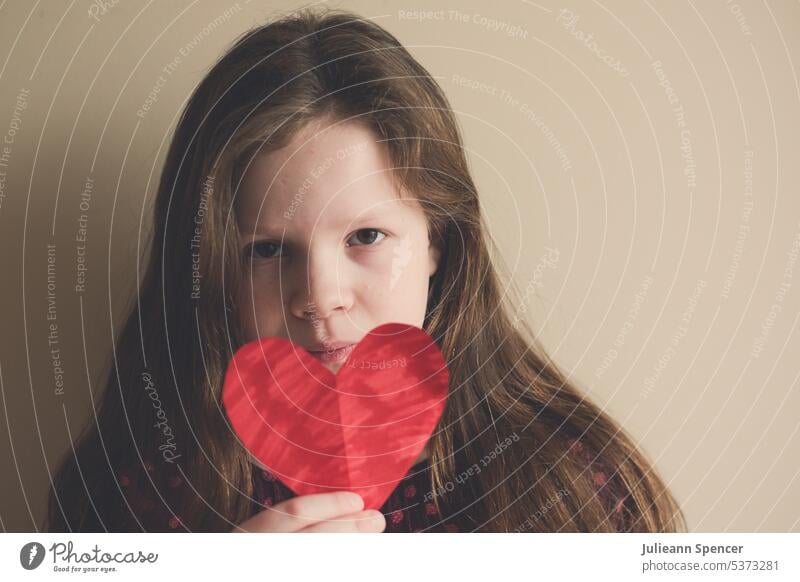 Young girl holding a cutout coloured in heart heartshape cutout heart red heart cutout heart shape child attentive stare Heart Love Red Valentine's Day Romance