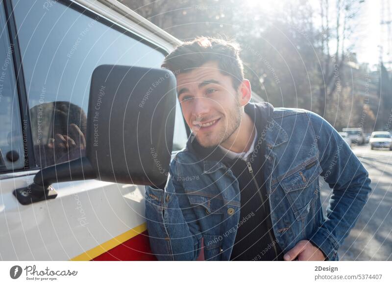 A Young man is pleased to see his handsome looks on the side mirror of a car. check confident guy hispanic horizontal model outside standing stylish van vehicle