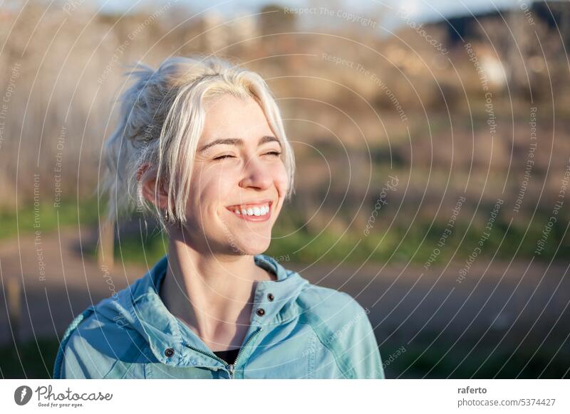 A Portrait of smiling blonde woman with eyes closed after jogging ponytail portrait person beautiful young runner toothy female sport smile caucasian happy