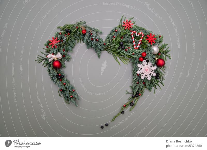Christmas composition. Heart symbol made of pine, cypress, thuja branches branches, balls, berries and wood decorations. Christmas, winter, new year concept. Flat lay, top view, copy space