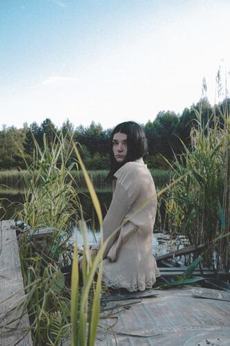 by a pond Self portrait dark hair old boat lake Water Nature girl Trees on the horizon Calm Sky blue and green