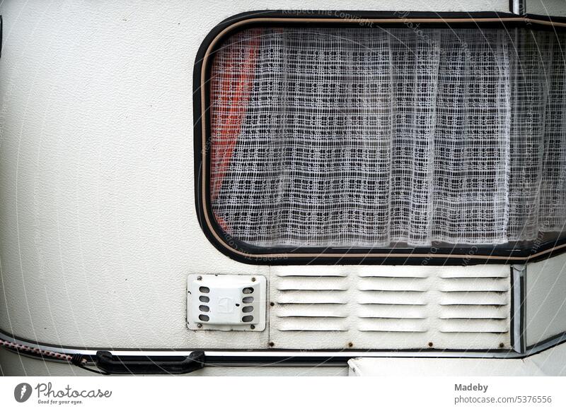White caravan for vanlife and camping with curtain on the window in the style of the early fifties in the steering plant in Bielefeld in the Teutoburg Forest in East Westphalia-Lippe