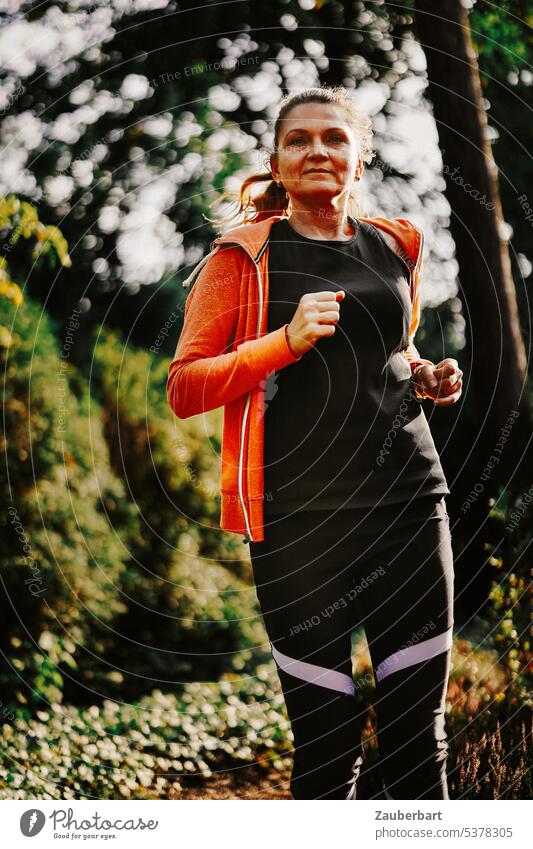Woman jogging in forest Jogging Sports Walking Forest Nature Orange Back-light Fitness Athletic Healthy workout Lifestyle Runner Running pretty Practice Adults