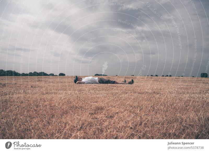 Man lying on the ground in a harvested field man lying down sleeping outdoors lifestyle summer nature person crop asleep outside male rest relax comfortable
