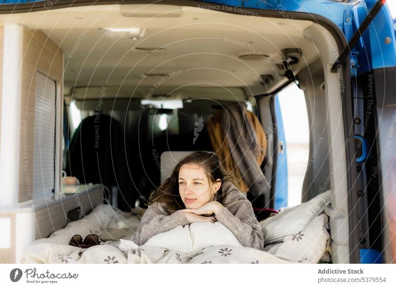 Thoughtful woman lying in camper van during trip traveler holiday blanket car summer rest female vacation young journey nature adventure pensive recreation