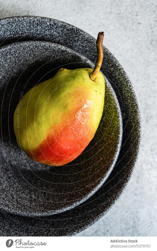 Healthy pear fruit in plates against gray background bowl concrete diet gourmet healthy nutrition one only organic raw ripe seasonal stoneware summer superfood