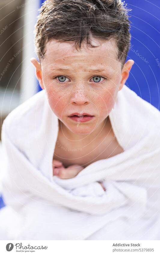 Serious kid sitting with towel covered on body child boy upset worried rest wet hair lounger shirtless summer vacation childhood park serious weekend daytime