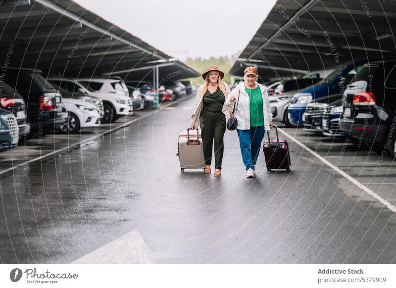 Elderly women with suitcases walking on parking lot vacation luggage traveler together happy trip asphalt journey holiday tourism female road smile baggage