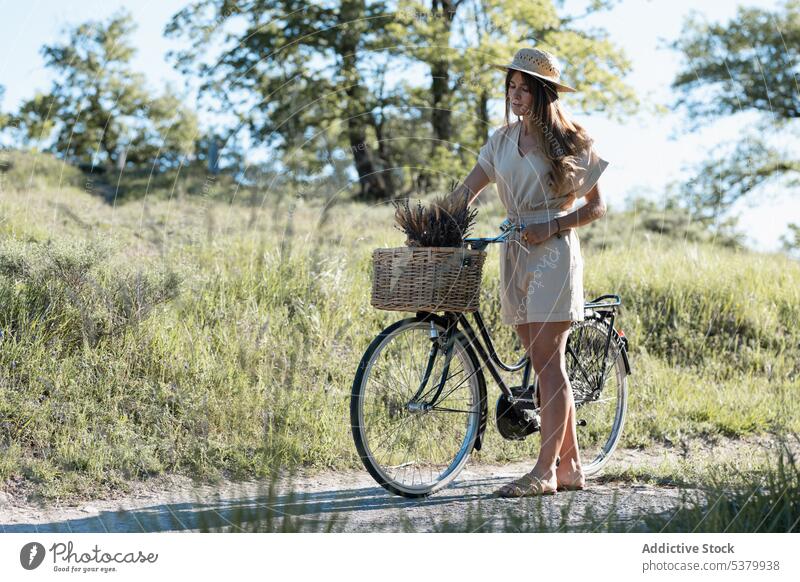 Young woman standing with bicycle in countryside straw hat wicker basket wheat spike shadow summer young female nature style rural bike sun road summertime