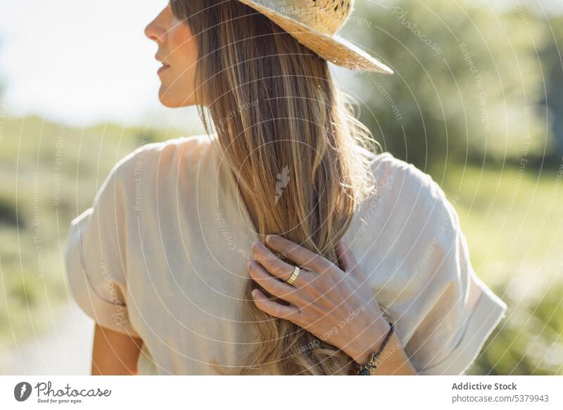 Young woman in straw hat standing in countryside smile touch head portrait happy vacation optimist glad summer young female cheerful sunlight gesture positive