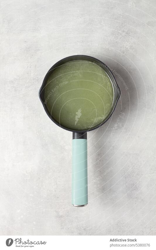 Pan with watery green broth kitchenware table enamel pan shape circle round juice paste handle utensil equipment minimal simple creative prepare design fresh