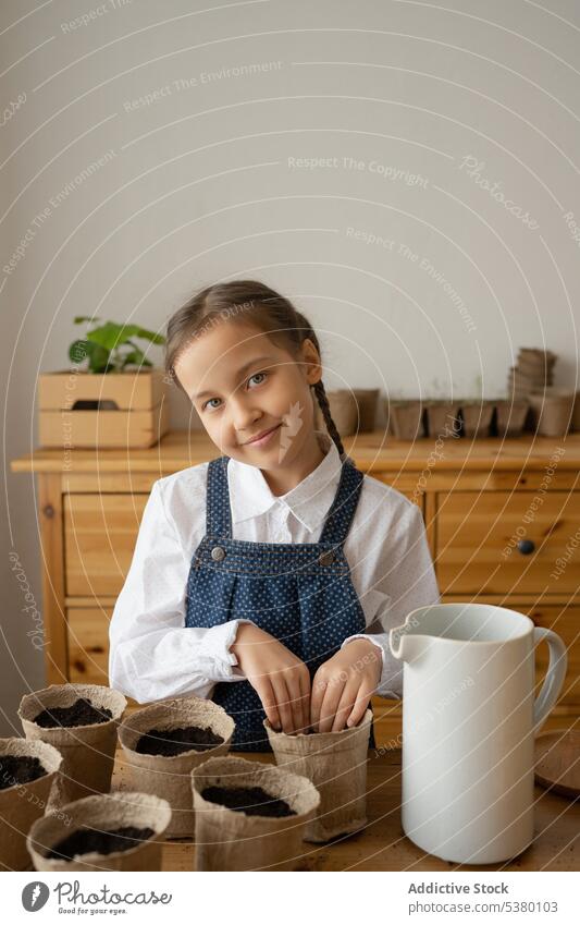 Cute little girl with loamy soil in flexible planting cups on table cute home pot garden positive work horticulture child kid wooden childhood adorable casual