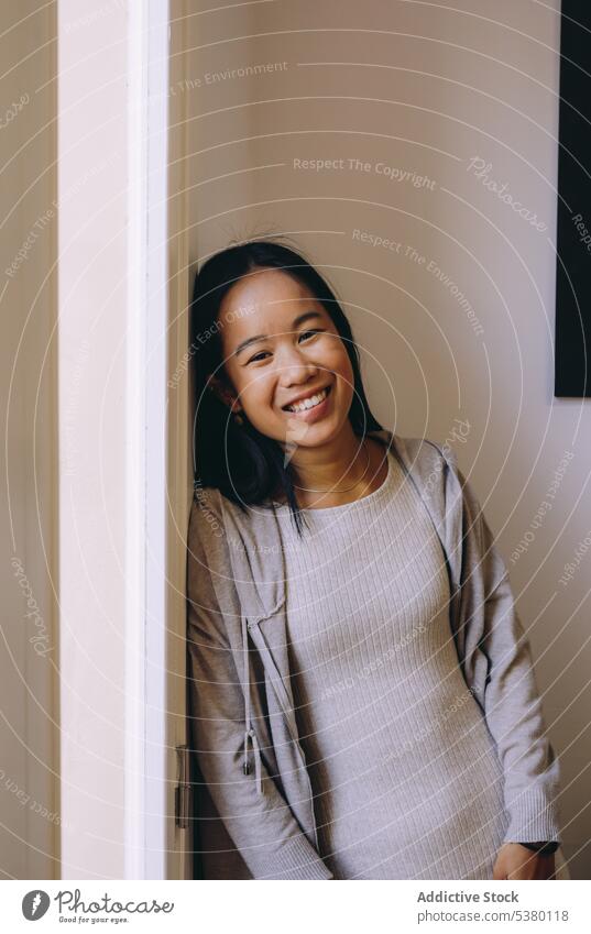 Smiling Asian woman in casual cloth smile room positive window happy rest home cozy glad ethnic female cheerful young optimist apartment joy delight relax